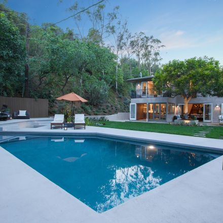 A serene backyard featuring a sparkling pool surrounded by lush greenery and a well-maintained landscape.
