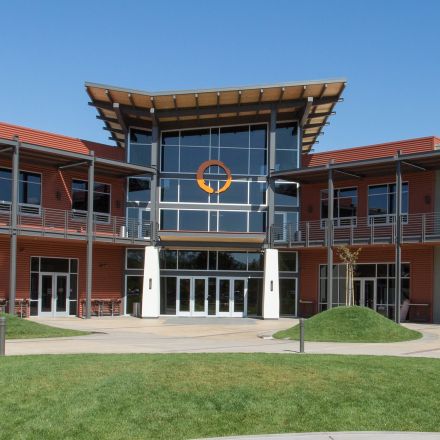 A building's facade is visible, surrounded by a spacious grassy area, creating a welcoming outdoor environment.