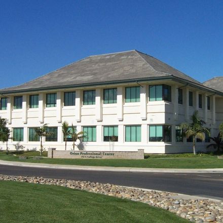 A white building stands prominently against a clear blue sky, showcasing its clean and modern architectural design.