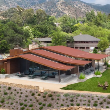 A modern pavilion showcasing innovative architecture amidst lush greenery and vibrant animal exhibits.