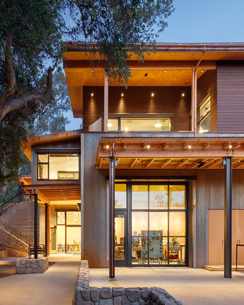 A modern home exterior featuring sleek lines and a large tree providing shade and natural beauty in the landscape.